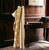 Rolls of fabric set against panelled wall with wooden side table and album