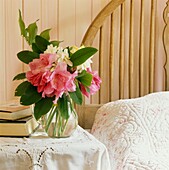 Vase of flowers on lace-covered bedside table