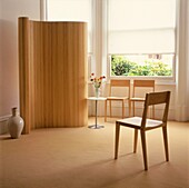 Drei Holzstühle in einem abgedunkelten Raum mit Bambuswand