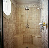Neutral tiled shower room with seating and a porthole window