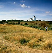 Man walking over moorland to lighthouse 