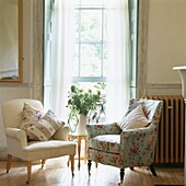Armchairs with contrasting fabrics at open sash window with fern arrangement
