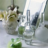 Perfume bottles and vase of flowers with mirror on dressing table