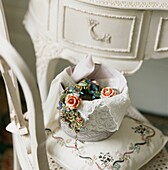 Rose jewelled necklace in china bowl with lace on chair with embroidered cushion