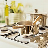 Metal saucepan with wooden spoon on gas hob
