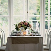 Place settings with flower arrangement in front of window
