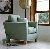 Pastel coloured armchair with Oriental lamp at open sash window