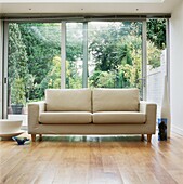Large cream sofa in front of double glass sliding doors on to garden