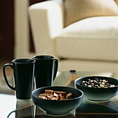 Two cups with bowls of confectionary on glass topped coffee table