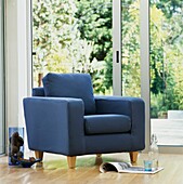 Blue upholstered armchair on laminate floor with sliding patio doors