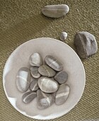 Stilleben mit Kieselsteinen in einer Schale auf einem Kokosteppich