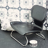 Low leather chair on steel frame with decorative printed fabric and wallpaper