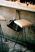Handbag hanging on a hook underneath a bar counter beside a padded bar stool in a Spanish Tapas bar