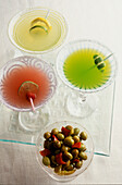 "Tequila Cocktails; links Granatapfel Margarita oben Golden Margarita rechts Midori Margarita und eine Schale mit Oliven"""