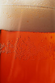 Detail of side of glass of beer with frothy head