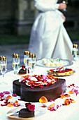 Ein herzförmiger Schokoladen-Hochzeitskuchen, der mit Rosenblättern bestreut ist