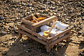 Hölzerner Korb mit Lebensmittelkartons am Strand