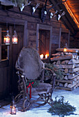 Sessel aus Geweihhorn vor einer Blockhütte mit Laternen