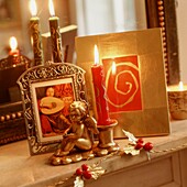 Cherub figurine and lit candle with picture on mantlepiece
