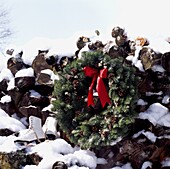 Log pile with Festive Evergreen wreath in snow