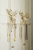 Jewellery hanging from stag head clothes hooks on panelled wall