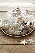 Large assortment of pretty christmas tree decorations in a dish on a tabletop