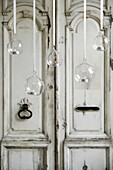 Clear glass baubles hanging on ribbons with twinkling tealights in front of an old ornate panelled front door