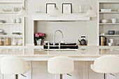 Bar stools in kitchen with white panelled shelving in contemporary home