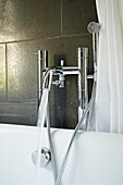 Glänzende Metallarmaturen in einem grau gefliesten Badezimmer