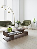 Grüner Sessel und Sofa im Retrostil im Wohnzimmer mit weiß gestrichenen Dielen