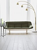 Green retro style sofa in living room with painted white floorboards
