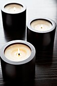 Three lit candles in dark wood candle holders