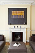 Ottoman at fireplace with modern art in contemporary London home