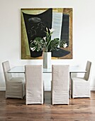 Tisch und Stühle mit Glasplatte und Bezügen im Esszimmer mit Kunstwerken in London