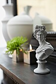 Grey female bust and lit candle on mantlepiece in London home   UK