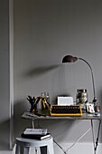 Vintage-Schreibmaschine und -Lampe auf dem Schreibtisch im Home-Office