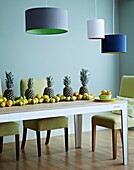 Pendant lampshades hang above a dining table of fruit