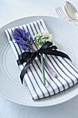 Cut flowers with striped napkin and black bow on place setting