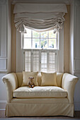 Teddybear on two seater sofa at window in Washington DC home,  USA