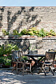 Wooden garden furniture in walled brick exterior of Greenwich home,  London,  England,  UK