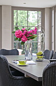 Rosa Blumen mit lindgrünen Teetassen auf einem Esstisch in einem modernen Haus in Haywards Heath, West Sussex, England, UK