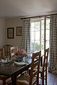 Wooden dining table and chairs with view to garden from Ashford home,  Kent,  England,  UK