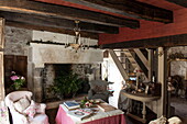 Offenes Wohnzimmer mit Balkendecke und großem Kamin in einem Bauernhaus aus Stein, Dordogne, Frankreich