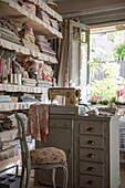 Fabric on shelves with sewing machine and open door in farmhouse interior,  Dordogne,  France