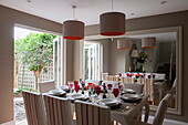 Tisch für acht Personen mit roten Weingläsern, reflektiert in einem großen Spiegel in einem Haus in Battersea, London, England, UK