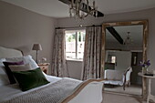 Green velvet cushion on double bed  with full frame mirror in Kingston home,  East Sussex,  England,  UK