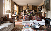 Metal bowl and magazines on ottoman with tapestry cushions in open plan living room of Dordogne country house  France