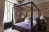 Dark wooden four-postered bed at window in Dordogne country house  France