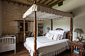 Himmelbett aus Holz mit Kinderbett in einem Schlafzimmer mit Natursteinmauer in der Dordogne Perigueux Frankreich