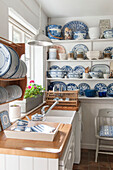 Blaues und weißes Porzellan mit Tellerregalen am Fenster in einer Küche in Dorset, Kent, Großbritannien